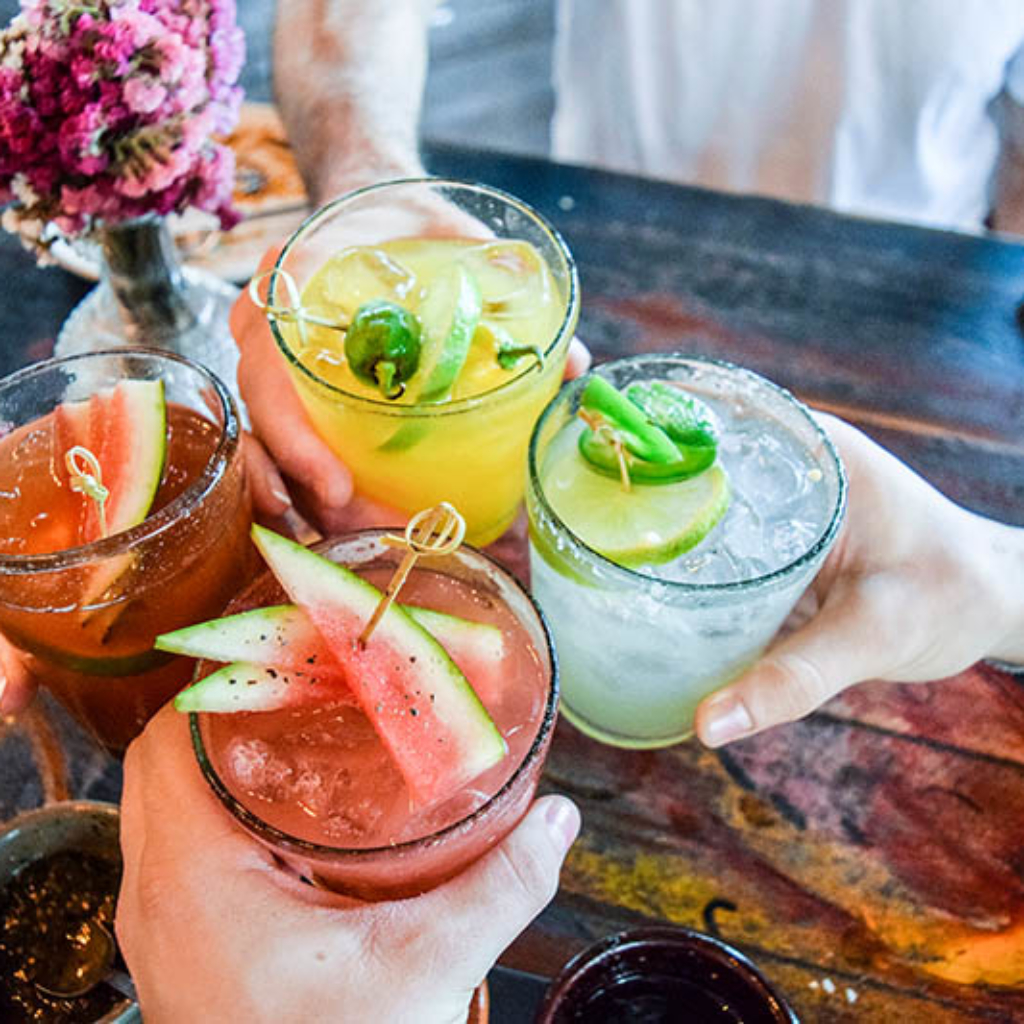 Friends toasting, saying cheers holding tropical blended fruit margaritas.  Watermelon and passionfruit drinks.; Shutterstock ID 780298633