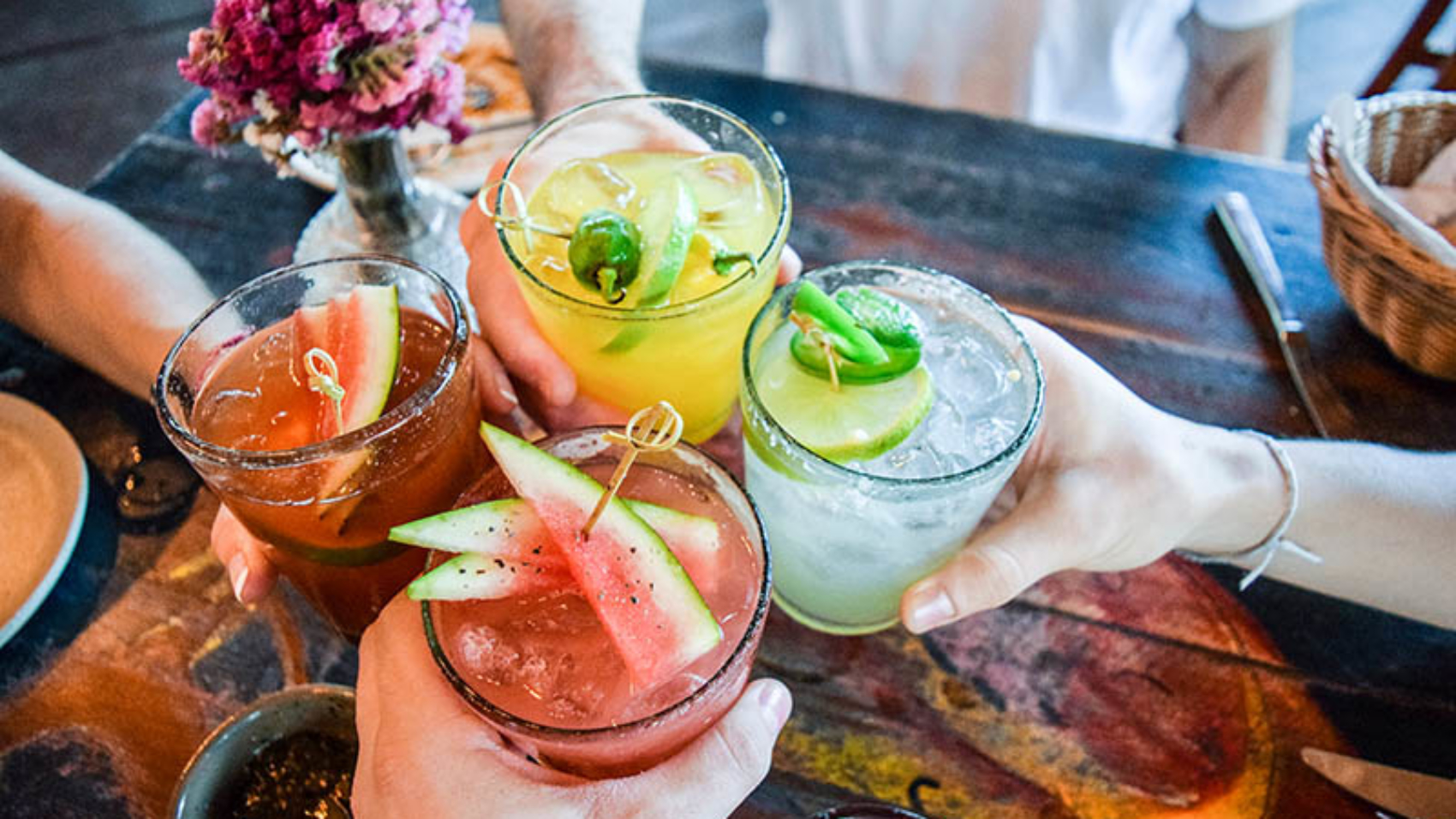 Friends toasting, saying cheers holding tropical blended fruit margaritas.  Watermelon and passionfruit drinks.; Shutterstock ID 780298633